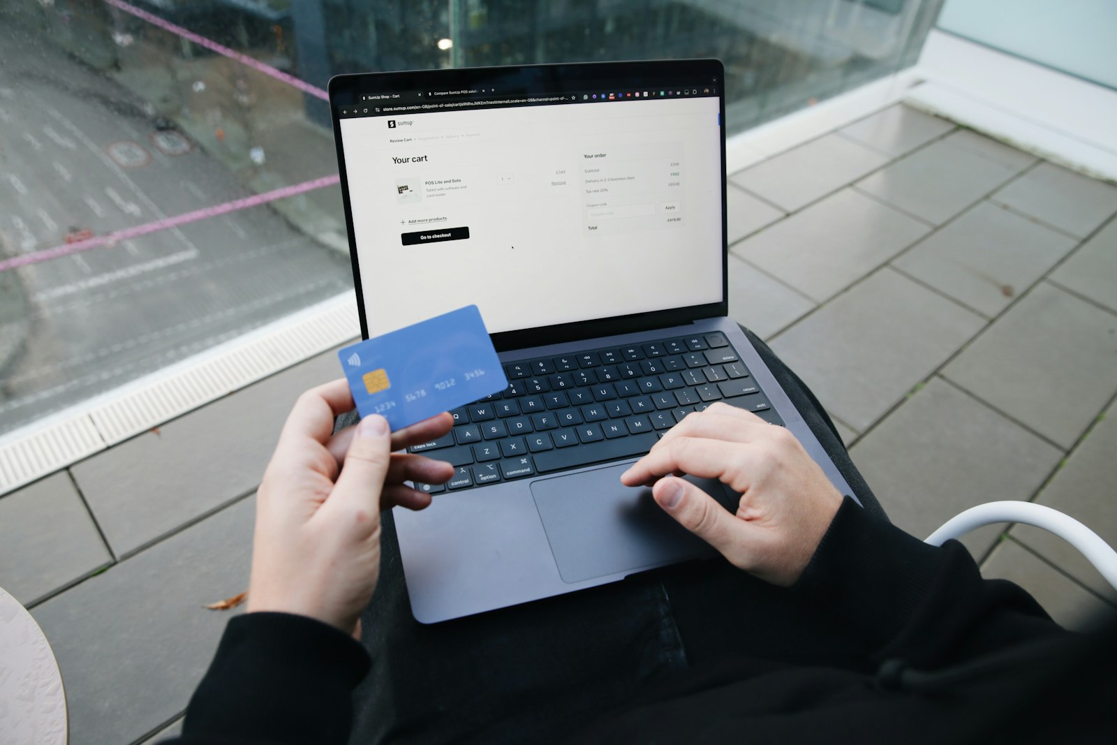 Pessoa sentada com notebook e cartão na mão